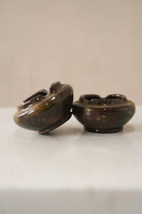 Two brown ceramic bowls on a white surface with a beige background