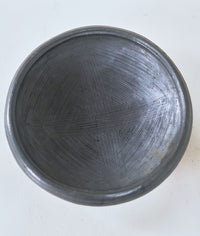 Black earthenware bowl with textured surface on a white background