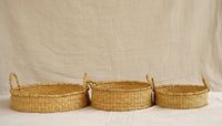 Three woven baskets of different sizes on a neutral background