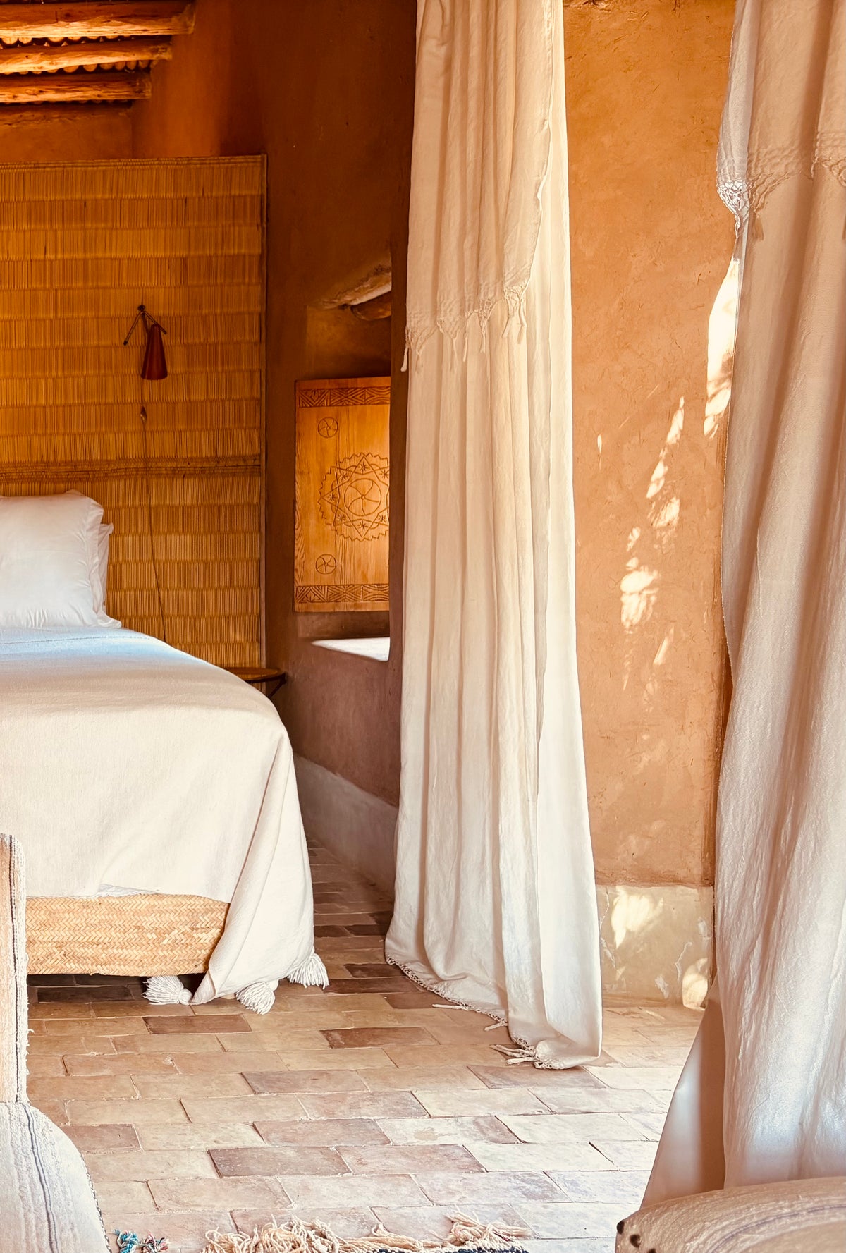 Bedroom with wooden headboard, white bedding, and light curtains.