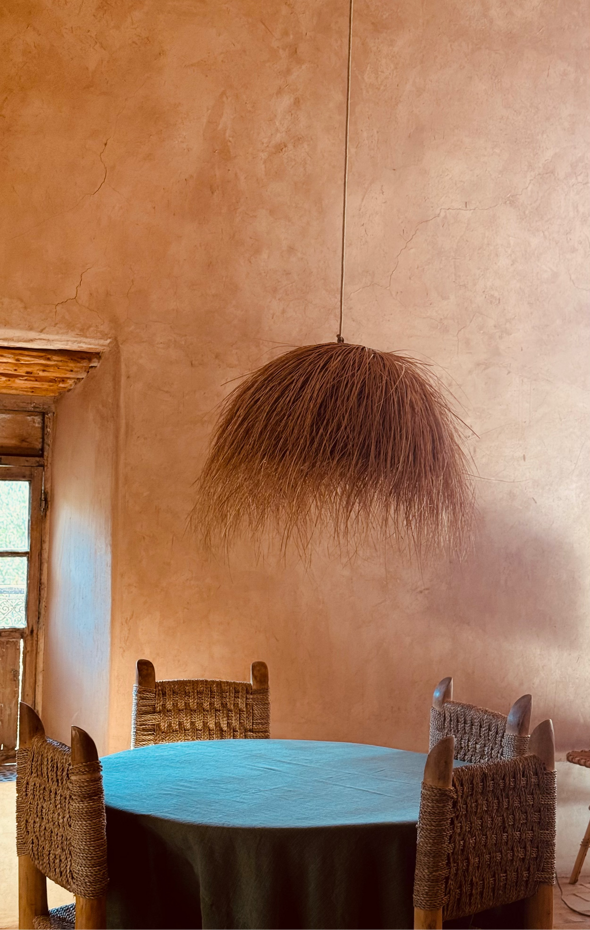 Dining area with round table and wicker chairs against a textured wall.