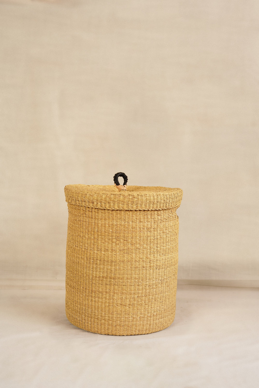 Woven basket with a lid on a beige background