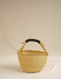 Woven basket with a black handle on a beige background