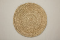 Round woven placemat on a beige background