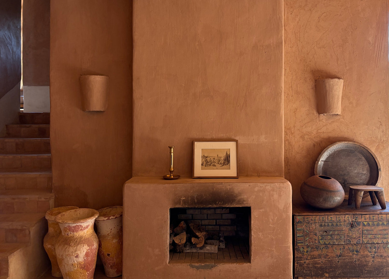 Ceramic pots and a small fireplace in a room with textured walls.