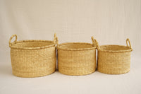 Three woven baskets of different sizes on a plain background