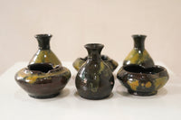 Set of ceramic vases with green and brown glaze on a white surface.