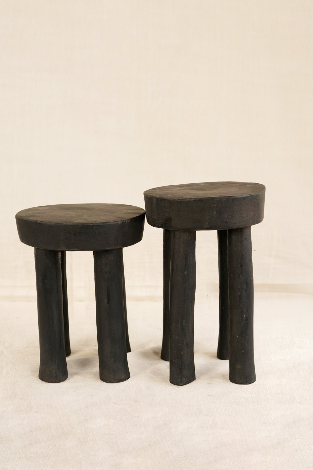 Two black stools with thick legs on a beige background