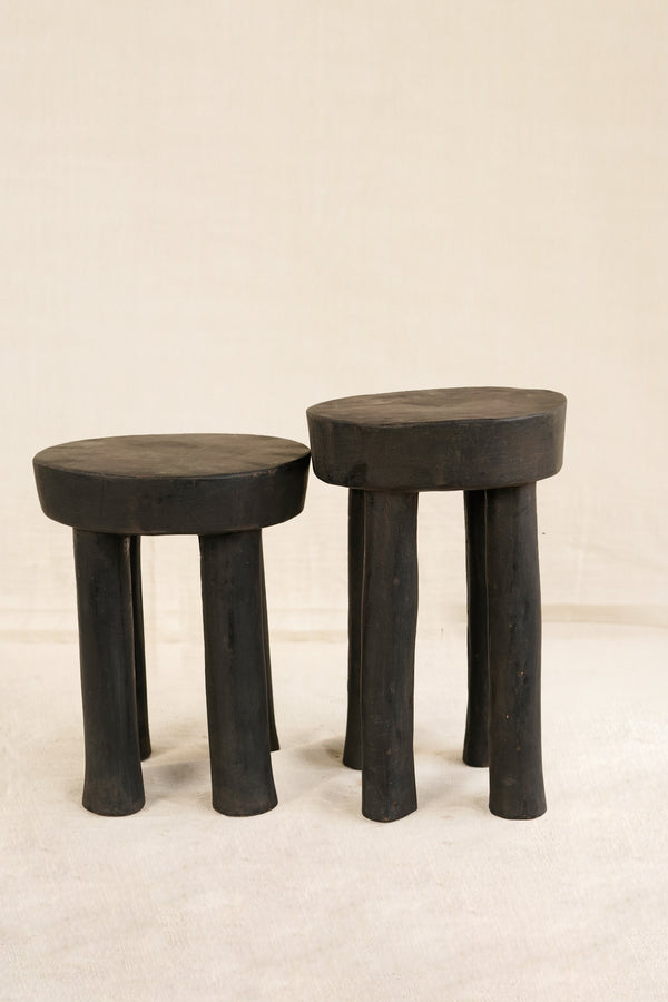 Two black stools with thick legs on a beige background