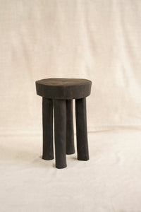 Black stool with three legs on a beige background