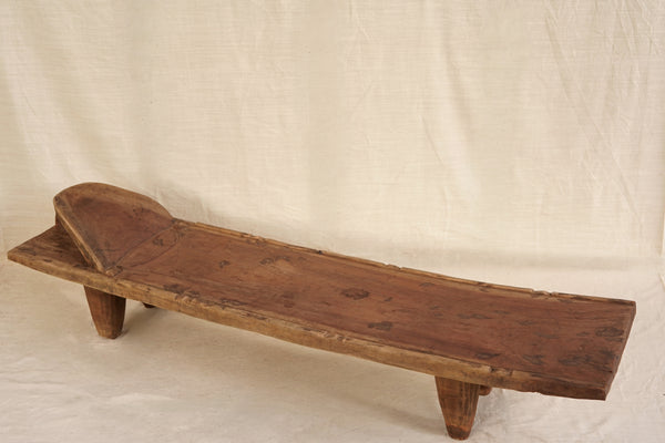 Wooden Senufo Bed with a beige linen background 