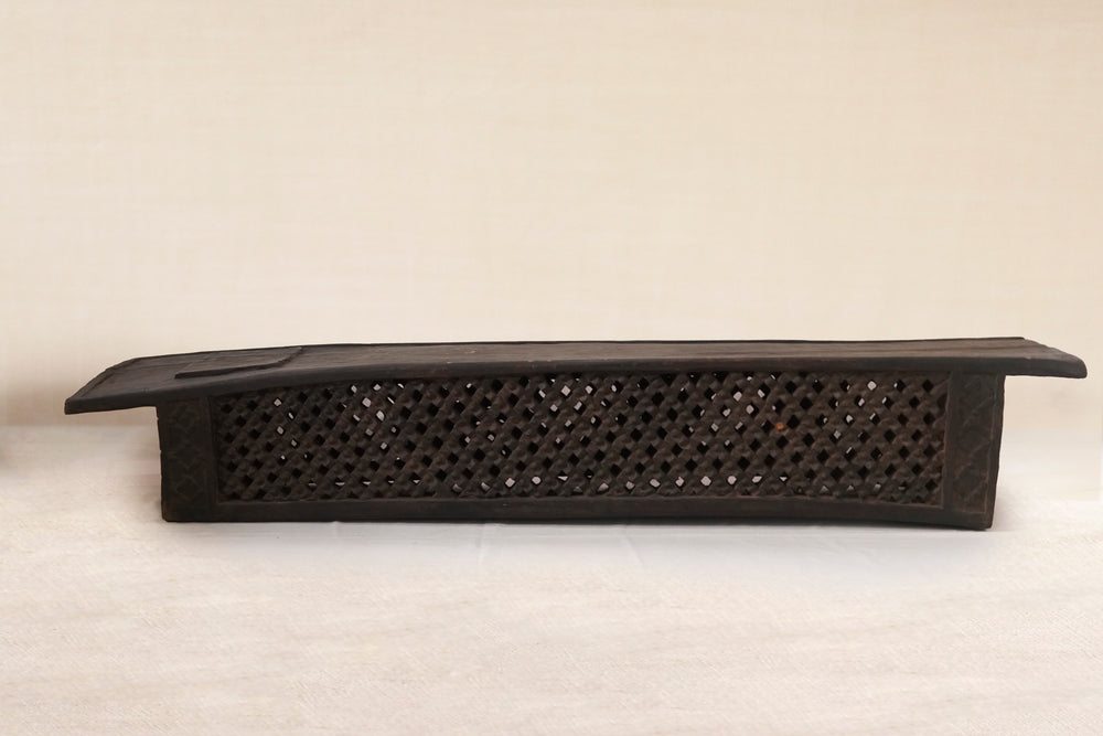 Black perforated  Bamileke bed on a beige background